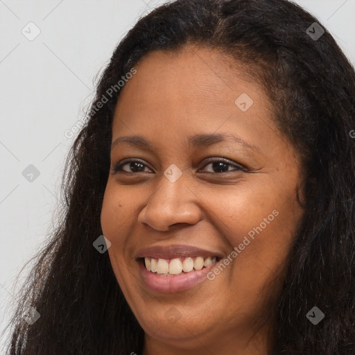 Joyful black young-adult female with long  brown hair and brown eyes