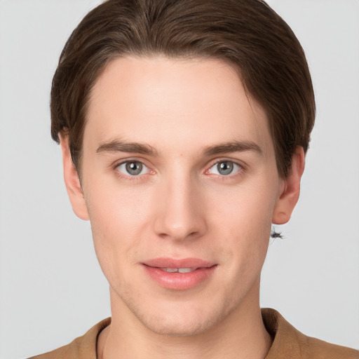 Joyful white young-adult male with short  brown hair and grey eyes