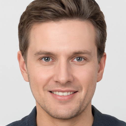 Joyful white young-adult male with short  brown hair and grey eyes