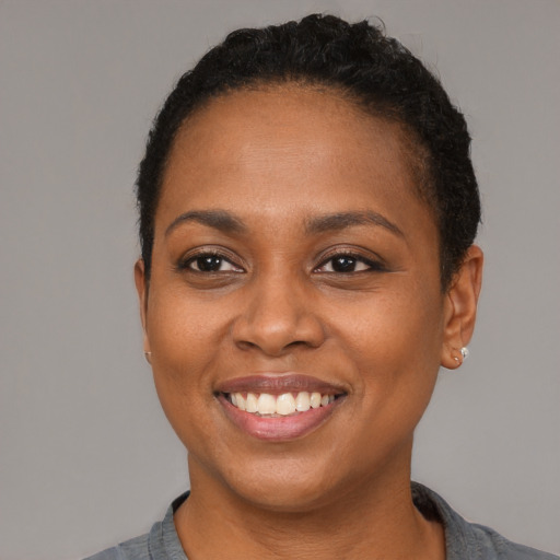 Joyful black young-adult female with short  black hair and brown eyes