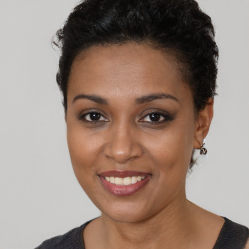 Joyful black young-adult female with short  black hair and brown eyes