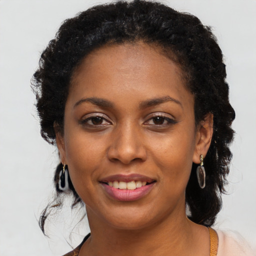 Joyful black young-adult female with long  black hair and brown eyes