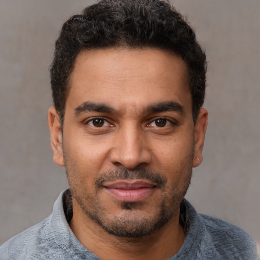 Joyful black young-adult male with short  brown hair and brown eyes