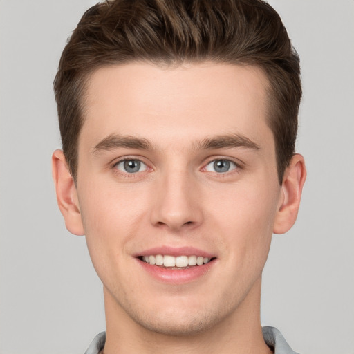 Joyful white young-adult male with short  brown hair and grey eyes