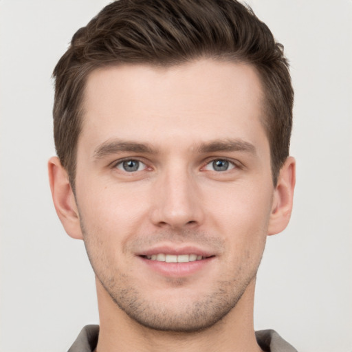 Joyful white young-adult male with short  brown hair and grey eyes