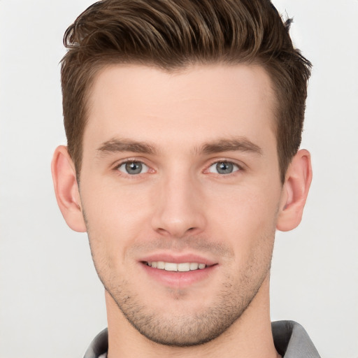 Joyful white young-adult male with short  brown hair and grey eyes