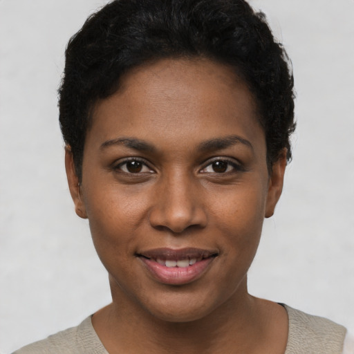 Joyful black young-adult female with short  black hair and brown eyes