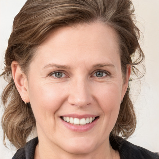 Joyful white adult female with medium  brown hair and grey eyes