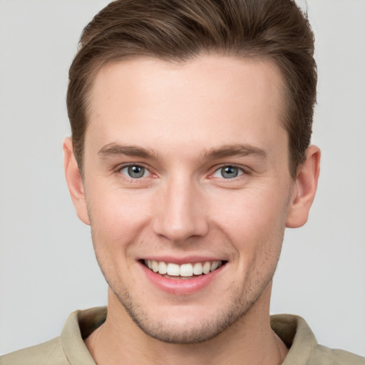 Joyful white young-adult male with short  brown hair and grey eyes