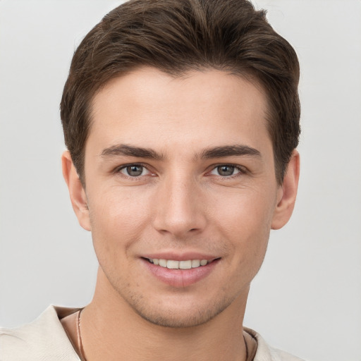 Joyful white young-adult male with short  brown hair and grey eyes