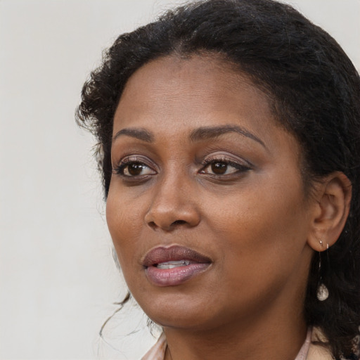 Joyful black adult female with long  brown hair and brown eyes