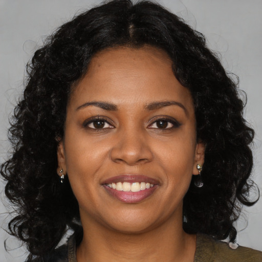 Joyful black young-adult female with long  brown hair and brown eyes