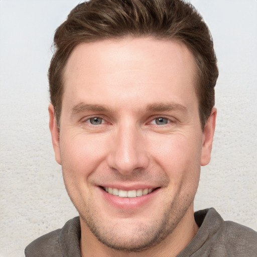 Joyful white young-adult male with short  brown hair and grey eyes