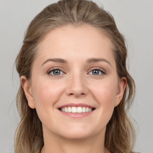 Joyful white young-adult female with medium  brown hair and grey eyes