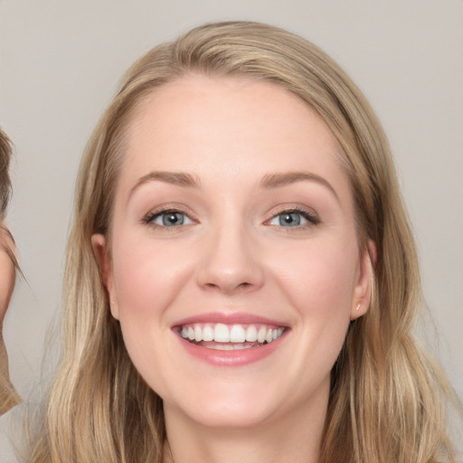 Joyful white young-adult female with long  brown hair and blue eyes