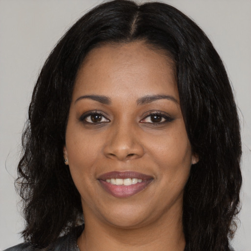 Joyful black young-adult female with long  black hair and brown eyes