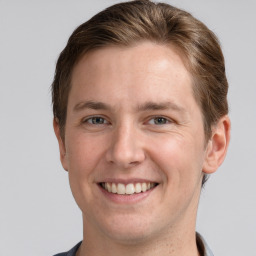 Joyful white young-adult male with short  brown hair and grey eyes