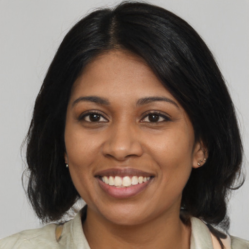 Joyful black young-adult female with medium  brown hair and brown eyes