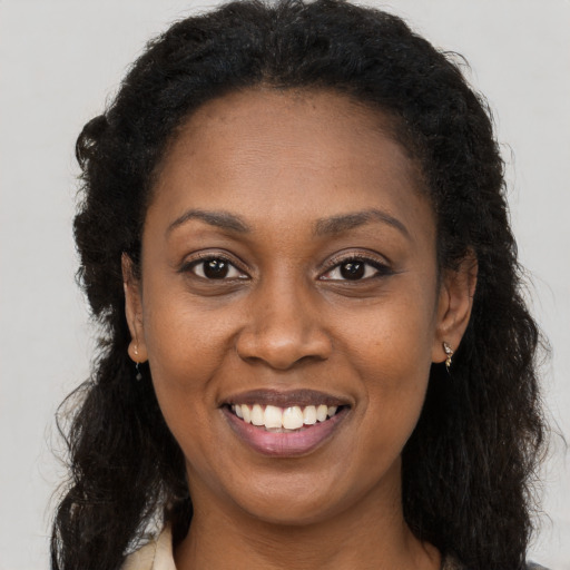 Joyful black adult female with long  brown hair and brown eyes