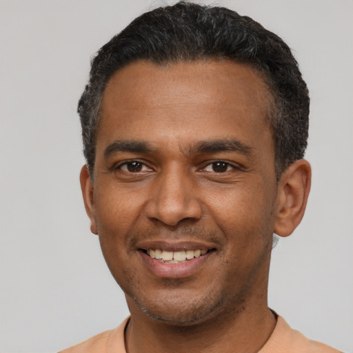 Joyful latino young-adult male with short  black hair and brown eyes