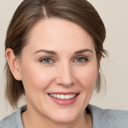 Joyful white young-adult female with medium  brown hair and grey eyes