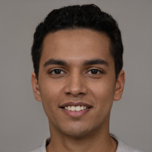 Joyful latino young-adult male with short  black hair and brown eyes