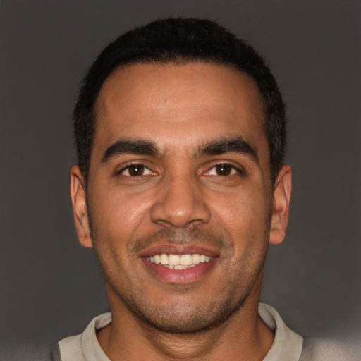Joyful black young-adult male with short  brown hair and brown eyes