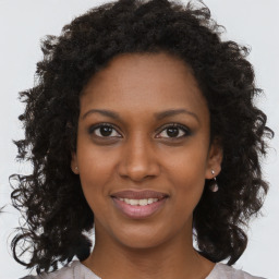 Joyful black young-adult female with long  brown hair and brown eyes