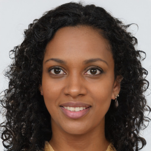 Joyful black young-adult female with long  brown hair and brown eyes
