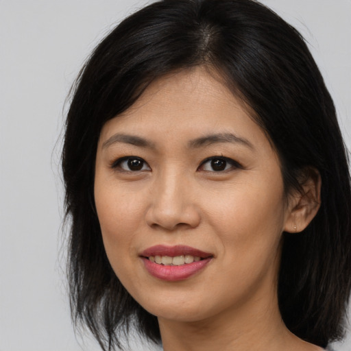Joyful asian young-adult female with long  brown hair and brown eyes