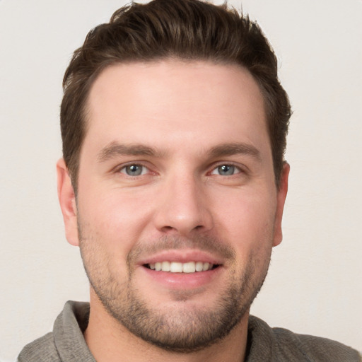 Joyful white young-adult male with short  brown hair and grey eyes