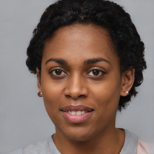 Joyful black young-adult female with short  black hair and brown eyes