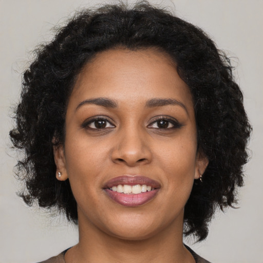 Joyful black young-adult female with long  black hair and brown eyes