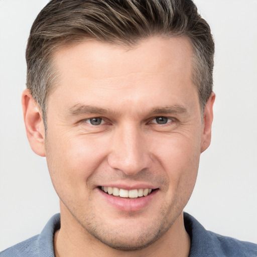 Joyful white young-adult male with short  brown hair and grey eyes