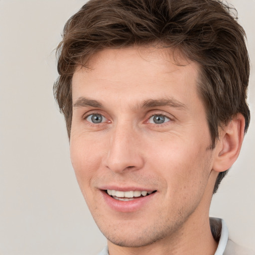 Joyful white young-adult male with short  brown hair and grey eyes