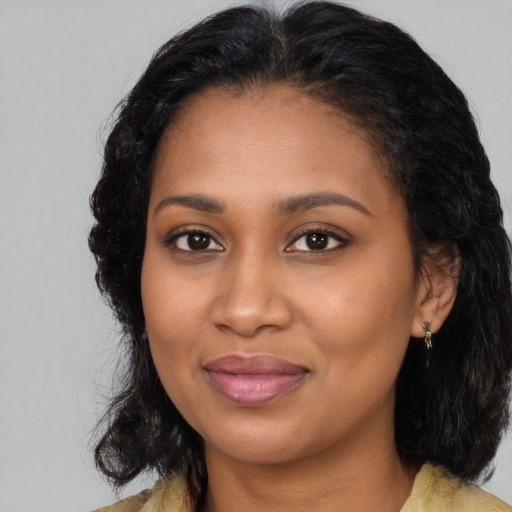Joyful black young-adult female with long  brown hair and brown eyes