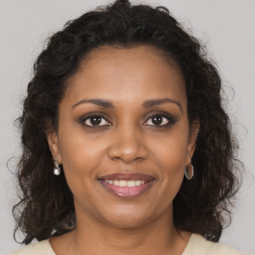 Joyful black young-adult female with long  brown hair and brown eyes
