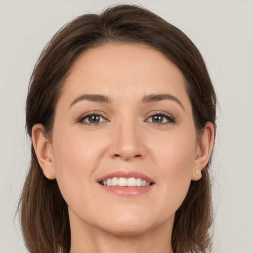 Joyful white young-adult female with medium  brown hair and grey eyes