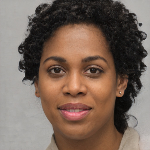 Joyful black young-adult female with long  black hair and brown eyes