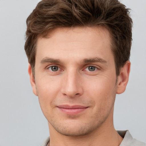 Joyful white young-adult male with short  brown hair and grey eyes