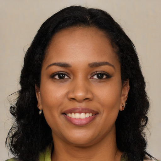 Joyful black young-adult female with long  black hair and brown eyes