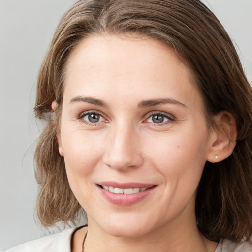 Joyful white young-adult female with medium  brown hair and grey eyes