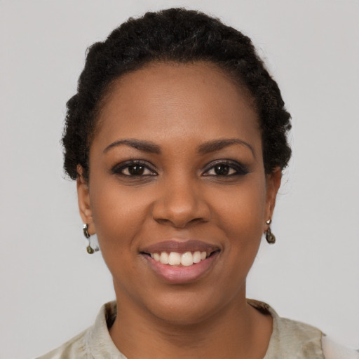 Joyful black young-adult female with short  black hair and brown eyes