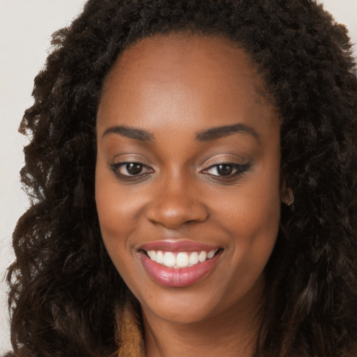 Joyful black young-adult female with long  brown hair and brown eyes