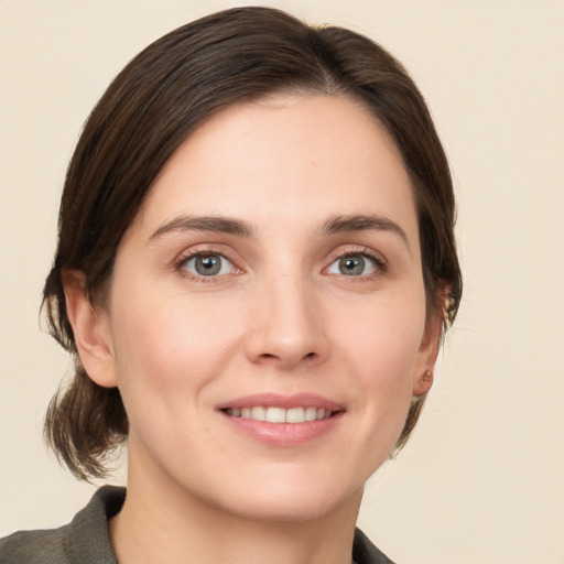 Joyful white young-adult female with medium  brown hair and grey eyes