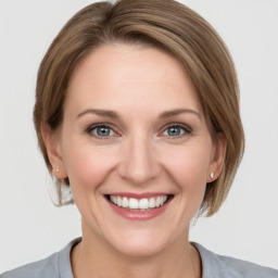 Joyful white young-adult female with medium  brown hair and grey eyes