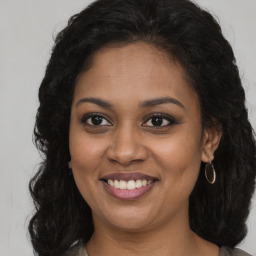 Joyful black young-adult female with long  brown hair and brown eyes