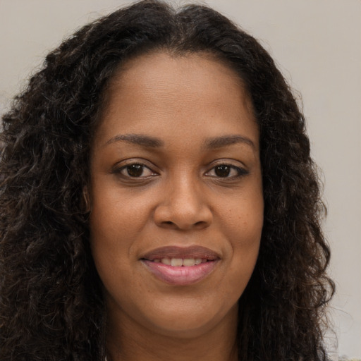 Joyful black young-adult female with long  brown hair and brown eyes