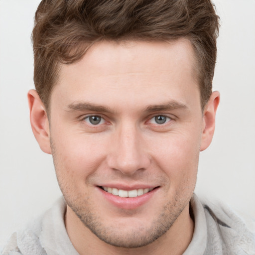 Joyful white young-adult male with short  brown hair and grey eyes