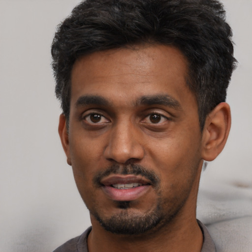 Joyful black young-adult male with short  black hair and brown eyes